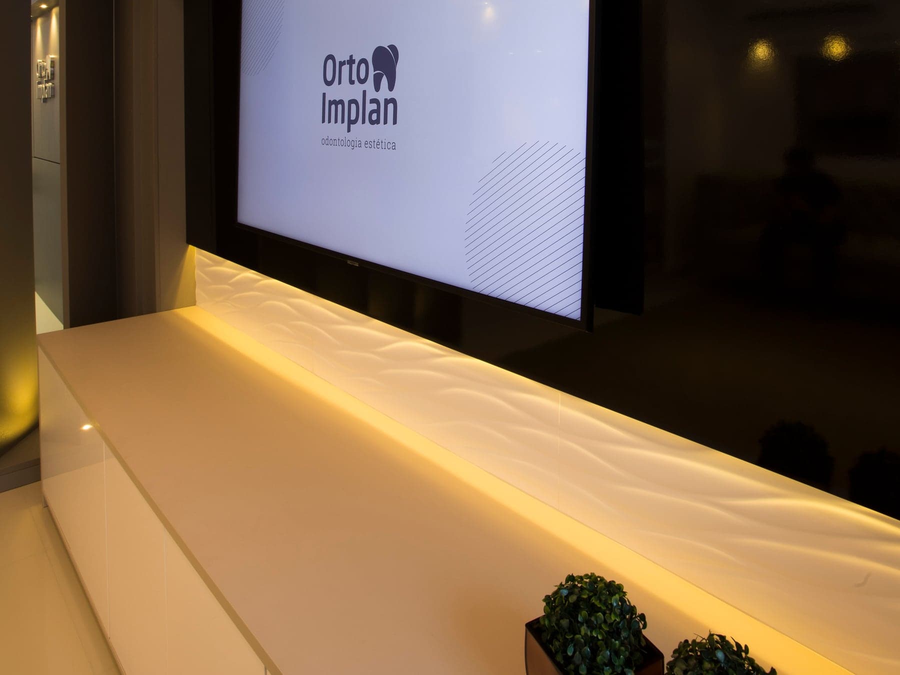 Ambiente Orto Implan com TV e identidade visual